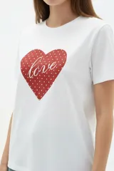 Remera de algodón blanca, de corte holgado, con cuello redondo y diseño estampado en el centro que incluye un gato comiendo de un plato y la inscripción 'Wild Cats'.