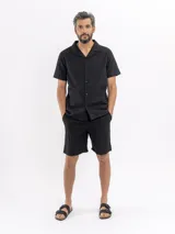 Camisa de manga corta color negro con sutil patrón tipo damero, cuello cubano y cierre frontal con botones.