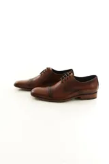 Zapato de vestir acordonado de cuero vacuno marrón, con puntera distinguida y suela con sutil tacón.