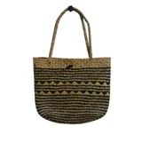 Cartera tipo tote bag tejida en fibras naturales, con diseño geométrico en tonos negro y natural. Cuenta con dos asas largas trenzadas para llevar al hombro.