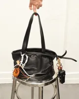 Llavero con dije de pretzel marrón, cordón blanco y negro, y detalles en cuero. Incluye mosquetón metálico para colgar en carteras o bolsos.