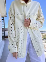 Sobrecamisa color manteca con calado geométrico, cuello camisero, cierre con botones y bolsillo de parche en el pecho.
