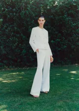 Pantalon de vestir de corte recto y diseño largo, confeccionado en tejido fluido de color blanco. Cuenta con dos bolsillos laterales y cierre oculto de botón, gancho y cremallera.