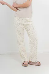 Pantalón de denim color crema con estampado de pequeñas flores rosas y verdes. Corte recto, tiro alto y calce relajado.