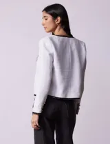 Chaqueta de tweed negra marca Nanette, con escote a la base, abertura central con botones, bolsillos delanteros, aplique de botones perlados en los puños, ribete en contraste blanco y forro interno.