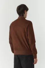 Campera bomber negra de simil gamuza, con cuello redondo, cierre frontal con cremallera, bolsillos laterales con cierre y puños elásticos.