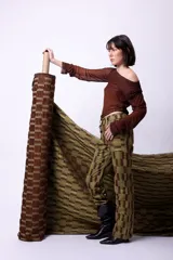 Pantalón de tiro alto con diseño de cuadros en tonos verde oliva y marrón, confeccionado en pana. Presenta una silueta de pierna recta, bolsillos plaqué y cierre frontal con botones metálicos.