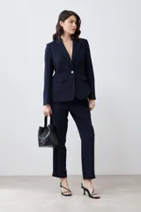 Blazer azul marino de corte clásico, con solapa de muesca, un botón dorado frontal y bolsillos de solapa.