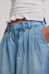 Pantalón de denim celeste de tiro bajo, pierna muy ancha y diseño sastrero con tablas al frente. Cuenta con cintura fruncida en la espalda, bolsillos y cierre frontal con cremallera y gancho.