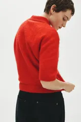 Remera polo de manga corta confeccionada en punto suave con mezcla de mohair y lana, color rojo, con cuello clásico, tapeta con botones frontales y ribetes acanalados.