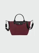 Cartera de mano modelo Le Pliage Energy en tamaño S, color verde oliva. Presenta solapa y asas de cuero negro, cierre principal con broche a presión y correa ajustable extraíble con detalles en blanco y negro.