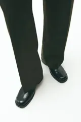 Pantalón de vestir color marrón oscuro, de corte sastrero con pinzas frontales, tiro alto y piernas amplias. Presenta cierre oculto con botón y corchete, bolsillos al bies y bolsillos traseros insertados.