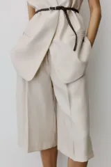 Bermuda de tiro alto en mezcla de lyocell, color beige, con piernas amplias, pinzas, raya planchada al frente y atrás, bolsillos al bies y bolsillos traseros insertados.