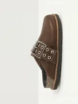 Zueco de cuero color chocolate, con diseño de punta redondeada y tira ajustable sobre el empeine con hebilla metálica y detalle de ojales decorativos.