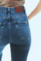 Pantalón de jean azul de tiro alto, corte semi oxford con botamanga ancha y abierta, y ruedo al corte.