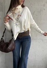 Sweater de punto color natural con cuello polera, manga larga y diseño holgado.