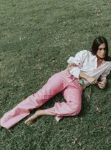 Pantalón de cuero color marrón con estampado abstracto, corte acampanado y abertura en el ruedo.