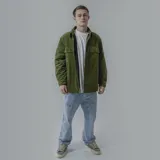 Campera color verde militar de pana con cuello clásico, cierre frontal con botones a presión y dos bolsillos de parche en el pecho. Interior forrado en negro.