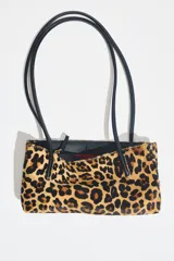 Bolso de hombro de piel con textura y estampado animal print, con doble asa larga negra y compartimento interior con cremallera.