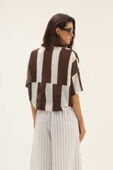 Camisa marrón y blanca a rayas verticales, con cuello mao y mangas cortas. Se ata en la parte delantera.