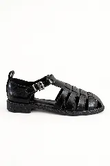 Sandalias tipo guillermina color negro, con diseño de tiras entrelazadas, talón cerrado, suela plana y tira ajustable con hebilla metálica en el lateral.