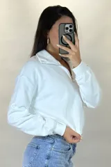 Buzo deportivo color blanco con cuello polo y cierre frontal parcial. Presenta mangas largas con puños elásticos y ruedo ajustable con cordón elástico.