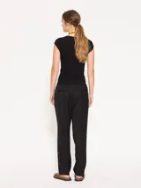 Pantalón negro de sarga, con elástico en la cintura, bolsillos laterales y ojal en la espalda.