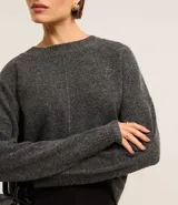 Suéter gris melange de punto con cuello redondo y manga larga.