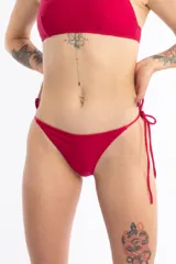 Bombacha de bikini roja, corte less, forrada y ajustable mediante lazos laterales.