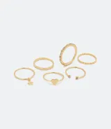 Set de seis anillos dorados con diferentes diseños: uno con dije de estrella, uno con forma de corazón, uno con strass, uno trenzado y dos con texturas.