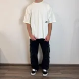 Remera color hueso con estampado de hongos y texto en la espalda, corte oversize.