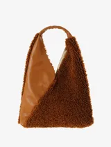 Cartera tipo hobo de gran tamaño, con forma envolvente y asa integrada. Presenta un diseño bicolor y de texturas mixtas: una sección es de cuero negro texturizado y la otra de material afelpado negro (tipo borrego o sherpa).