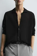Sobrecamisa de punto negro de corte relajado, con cuello solapa y manga larga. Presenta cierre frontal de botonadura y acabados en rib.