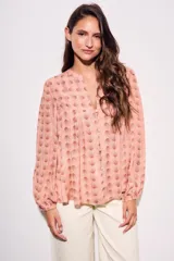 Blusa de corte oversize con estampado de abanicos, cuello redondo con pequeña abertura frontal, cierre de botones y mangas largas con puños elásticos.