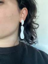 Aros colgantes con forma de gota alargada, color blanco.