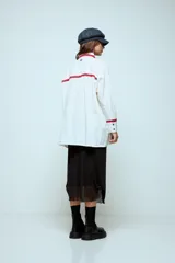 Camisa blanca de algodón con detalles de puntilla roja en cuello, solapa frontal, bolsillo y puños. Presenta botones en color celeste.