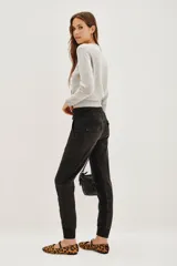 Pantalón tipo babucha de gabardina elastizada, color negro, con cintura elástica ajustable mediante cordón, puños en los tobillos, bolsillos diagonales frontales y bolsillos traseros con solapa y botón.