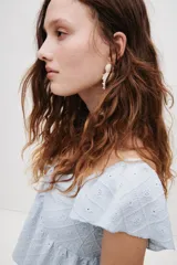 Blusa corta celeste de punto pointelle con textura, escote corazón, mangas cortas con vuelo y cordón de ajuste en el centro del busto.