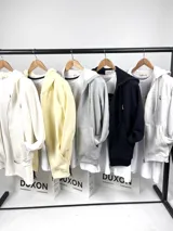 Campera con capucha de algodón grueso color amarillo patito, con cierre frontal y bolsillos tipo canguro. Presenta un pequeño logo bordado en el pecho.