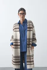 Cardigan largo de tejido de punto con diseño de rayas horizontales en tonos beige, marrón y blanco. Presenta una silueta relajada, mangas largas y frente abierto.
