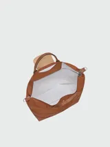 Bolso de viaje Longchamp modelo Le Pliage Original, de diseño ampliable, confeccionado en nylon negro con detalles en cuero marrón en las asas y solapa frontal con cierre de botón a presión. Incluye correa ajustable y extraíble.