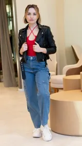 Chaqueta corta negra de cuero sintético, con cuello clásico, cierre frontal asimétrico con cremallera y bolsillos laterales con cremallera.