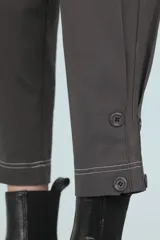Pantalón gris de corte cropped, con pinzas, costuras a contratono y tablas en los laterales sostenidas con cuatro botones.