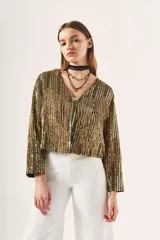 Saco corto dorado con bordado de lentejuelas y canutillos, escote en V y mangas largas.