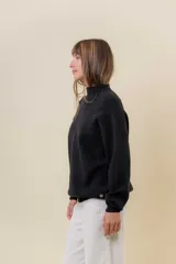 Sweater tejido de punto color blanco, con cuello alto y diseño en relieve tipo chevron en la parte frontal. Presenta un calce holgado con terminaciones acanaladas en puños y ruedo.