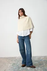 Capita de punto color crudo, con cuello alto vuelto y diseño amplio y corto.