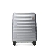 Valija rígida con diseño acanalado horizontal en color plateado. Presenta una estructura resistente con cuatro ruedas dobles que permiten un giro de 360 grados y un detalle en la parte superior con la inscripción 'PUSH'.