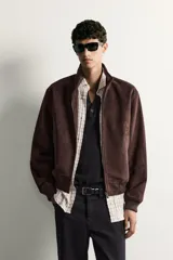Cazadora bomber de corte regular fit en tejido efecto ante de color marrón oscuro, con cuello alto, cierre frontal de cremallera y bolsillos laterales de vivo.