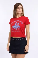 Remera corta amarilla ajustada al cuerpo, tipo baby tee, con estampado frontal negro estilo vintage que incluye la leyenda "Deloalto Club" y un diseño ecuestre.