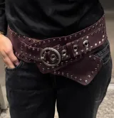 Cinto ancho de cuero color borgoña con tachas plateadas y hebilla circular.